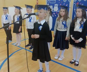 Uczennica klasy pierwszej przy mikrofonie, w tle pozostali pierwszoklasiści