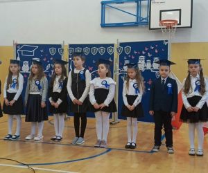 Pierwszoklasiści w strojach galowych z uczennicą klasy szóstej, prowadzącą uroczystość