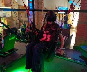 Dziewczynka w okularach VR, asekurowana linami wisi w powietrzu