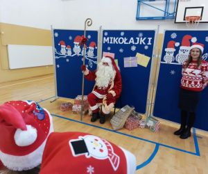 Święty Mikołaj i pani elf na tle tablicy dekoracyjnej