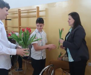 Uczniowie wręczają kwiaty