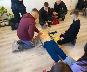 Dwóch uczniów prezentuje jak użyć defibrylatora AED