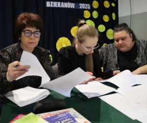 Na zdjęciu widoczna jest komisja konkursowa przeglądająca dokumentację.