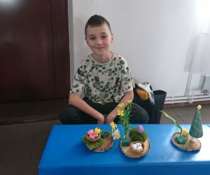 Na zdjęciu widoczny jest chłopiec wraz ze stroikami świątecznymi.