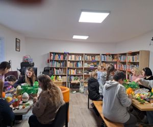 Na zdjęciu widoczna jest grupa osób uczestnicząca w warsztatach plastycznych.