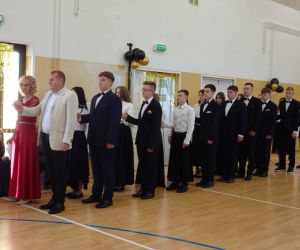 Wychowawca z innym nauczycielem prowadzą uczniów w pierwszych krokach Poloneza 