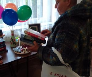 Zdjęcie przedstawia osobę dorosłą przeglądająca książki.