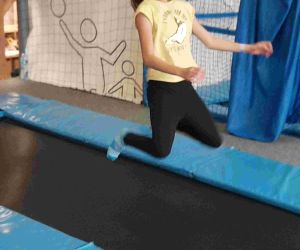 Uczennica klasy siódmej skacze na trampolinie