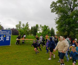 Uczniowie, rodzice i nauczyciele rozpoczynają próbę bicia rekordu w ilości okrążeń dookoła boiska