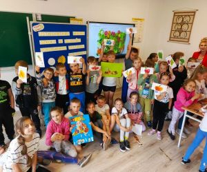 Uczniowie klas młodszych z nauczycielką prezentują swoje plakaty
