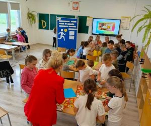 Uczniowie klas młodszych z nauczycielką przygotowują w grupach plakaty promujące zdrowe żywienie