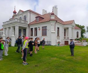 Uczniowie i nauczyciele zwiedzają z przewodnikiem teren dookoła pałacu w Czumowie