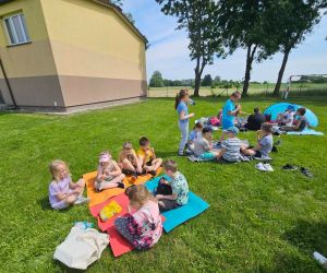 Dzieci siedzą na kocu na pikniku 