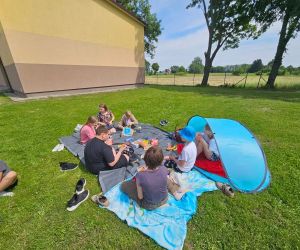 Dzieci siedzą na kocu na pikniku 