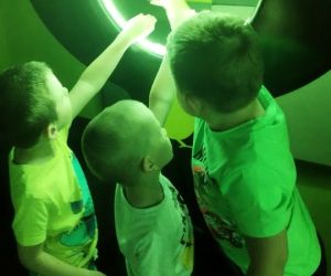 Trzech chłopców wkłada ręce do obręczy świetlnej