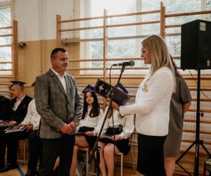 Dyrektor szkoły wręcza list gratulacyjny rodzicowi ucznia
