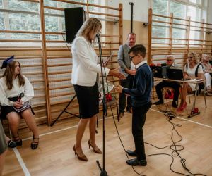 Dyrektor szkoły wręcza nagrodę książkową i świadectwo z wyróżnieniem uczniowi