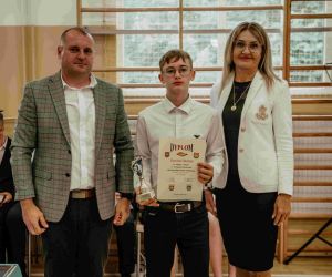 Dyrektor szkoły wraz z nauczycielem stoją obok zwycięzcy w turnieju szachowym