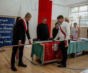 Absolwent szkoły wbija pamiątkowy gwóźdź do drzewca sztandaru