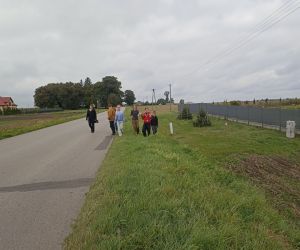Uczniowie pod opieką nauczyciela sprzątają pobocze.