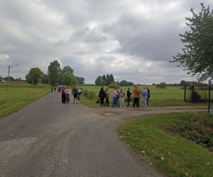Uczniowie zbierają śmieci przy drodze. 