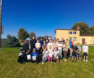 Grupa uczniów wraz z nauczycielem wychowania fizycznego pozuje do wspólnego zdjęcia na zakończenie sportowego dnia.