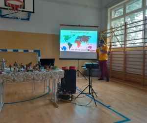 Prowadzący przy ekranie z mapą świata