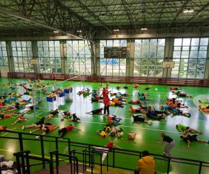 Młodzież wykonuje ćwiczenia rozgrzewające leżąc na podłodze