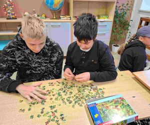 Dwóch uczniów układa puzzle przy stoliku