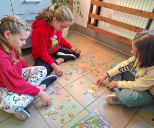 Trzy uczennice układają puzzle na podłodze