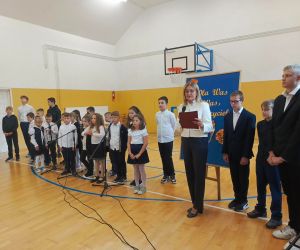 Pani Dyrektor przemawia stojąc przed grupą uczniów w strojach galowych