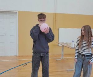 Uczeń wdycha gaz z balonika, obok stoi uczennica