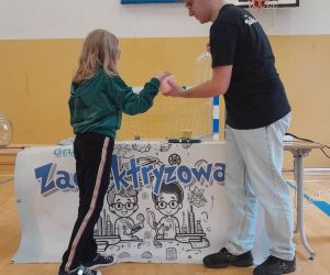 Prowadzący podaje uczennicy balonik