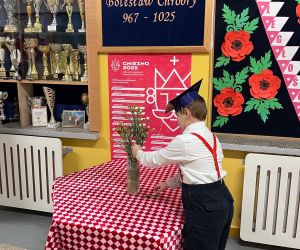 uczeń składa kwiaty przy wizerunku patrona szkoły