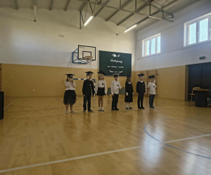 Pierwszoklasiści stoją w szeregu w sali gimnastycznej podczas uroczystości pasowania.