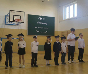 Grupa uczniów stoi na środku sali podczas części artystycznej.