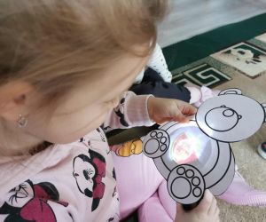 Dziecko oglądające ukryty obrazek w papierowym „misiu” podczas aktywności edukacyjnej.