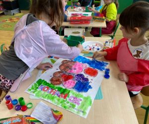 Przedszkolaki wykonujące wspólną pracę plastyczną przedstawiającą misia.