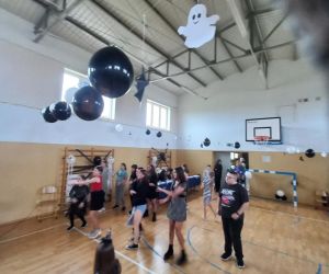 Uczniowie starszych klas tańczący na sali gimnastycznej podczas części tanecznej wydarzenia.