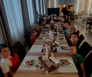 Przedszkolaki siedzące przy stolikach i przygotowujące pierniki do dekorowania.