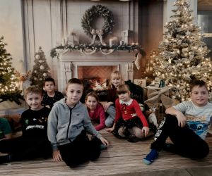 Uczniowie klas młodszych podczas wspólnego zdjęcia na tle kominka i zimowych ozdób.