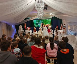 Aktorzy podczas jednej ze scen przedstawienia, w otoczeniu zimowej dekoracji i kukiełek.