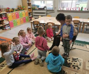 Przedszkolaki siedzą na dywanie i rozmawiają z panią po zakończonym czytaniu.