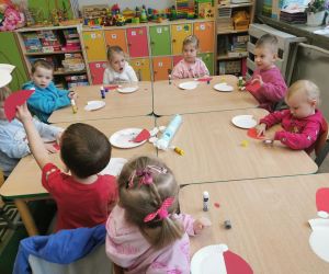  Dzieci podczas zajęć plastycznych układają papierowe elementy pracy przedstawiającej Mikołaja.