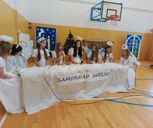 Uczennice przebrane za anioły siedzą przy stole