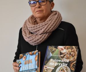 Kobieta na zdjęciu trzyma atlasy grzybów.