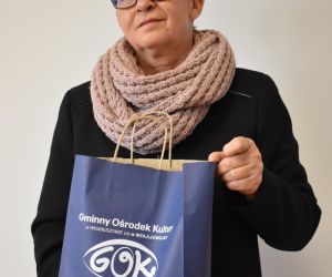 Kobieta na zdjęciu trzyma torbę prezentową z logiem GOK.