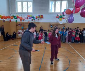 Uczennica odbiera walentynkę  na środku udekorowanej sali gimnastycznej, a pozostali uczniowie stoją wzdłuż ścian i obserwują wydarzenie.