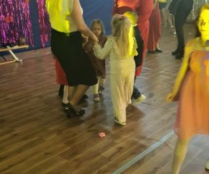 uczniowie tańczą w kółeczku z nauczycielkami