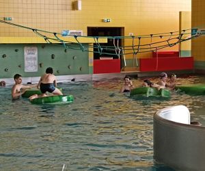 Uczniowie bawią się w basenie w Chełmskim Parku Wodnym, korzystając z pływających elementów rekreacyjnych.